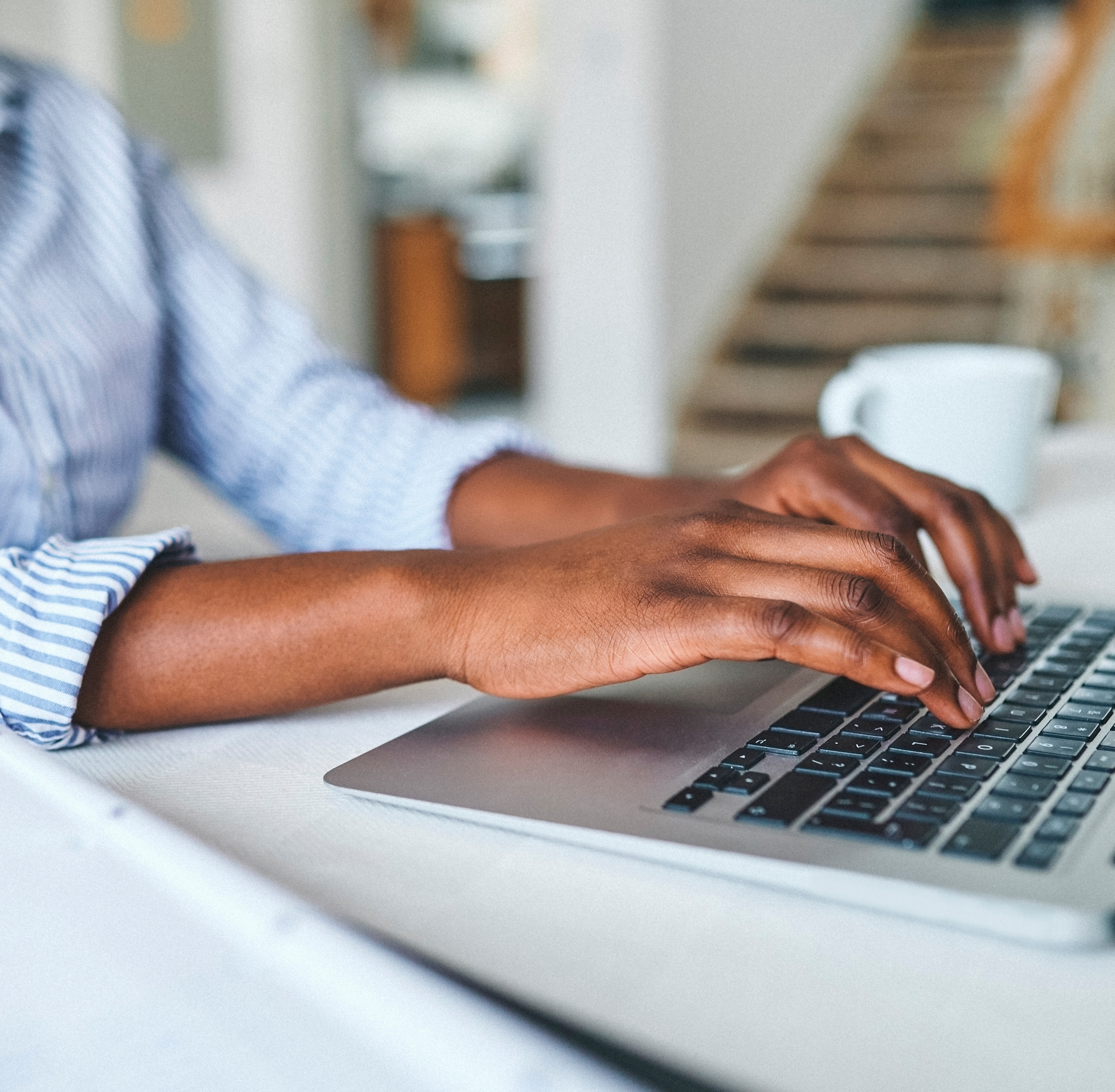 A black woman types on a laptop